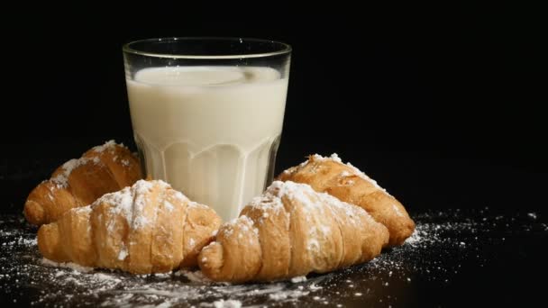Glass of milk with croissant rotate on a black background — Stock Video