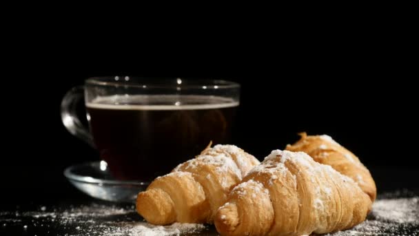 Kaffeepause. Croissants und Kaffee rotieren auf schwarzem Hintergrund — Stockvideo