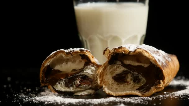 Glass of milk with halves croissant on a black background. hand puts a glass of milk background — Stock Video