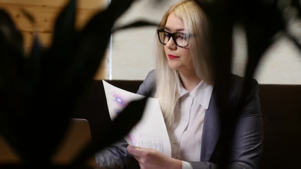 Giovane donna d'affari che lavora con computer portatile e documenti in caffè — Video Stock