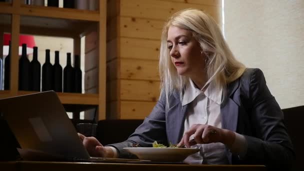 Деловая женщина обедает и работает на ноутбуке в кафе — стоковое видео