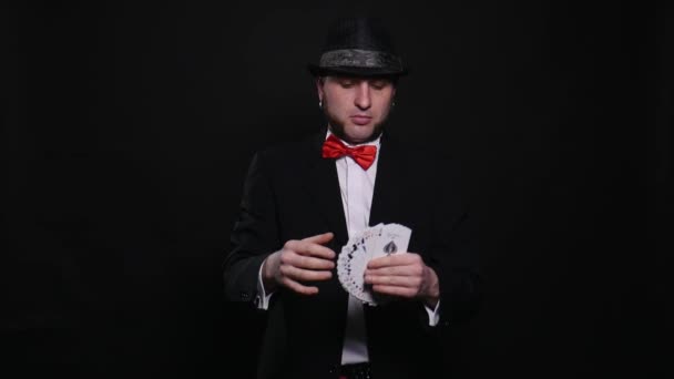 Joven mago muestra magia jugando truco de cartas truco de concepto de espectáculo sobre fondo negro — Vídeo de stock