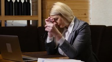 Kafede dizüstü bilgisayarda çalışması sırasında baş ağrısı olan genç iş kadını