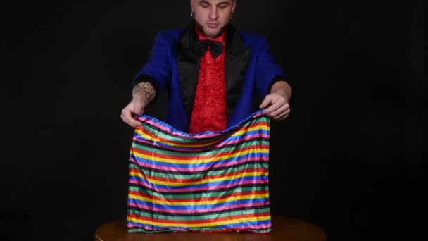 Magician shows trick with scarf and candle on dark background — Stock Video