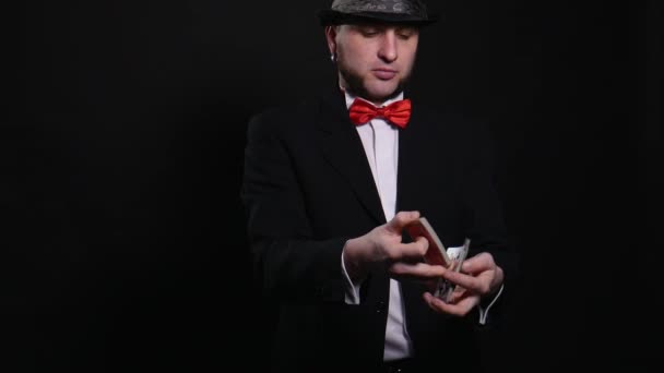 Jonge goochelaar toont speelkaart magische truc Toon begrip truc op zwarte achtergrond — Stockvideo