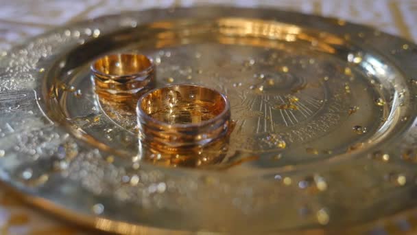 Close up of wedding rings of newlyweds during the consecration of holy water in the church before the wedding ceremony — Stock Video