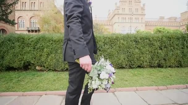 De bruidegom met het boeket in hand gaat — Stockvideo