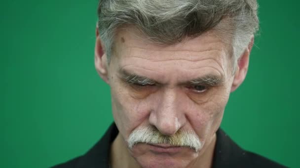 Smutny starszy mężczyzna na białym tle na zielonym tle. Portret studio z bliska — Wideo stockowe