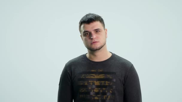 Angry young handsome man looking at camera over white background — Stock Video