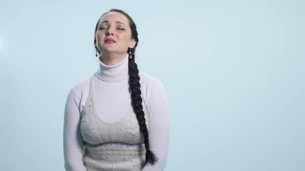 Молода сумна жінка плаче на білому тлі — стокове відео