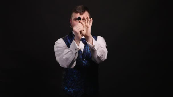 Goochelaar toont een truc met een lepel op zwarte achtergrond — Stockvideo