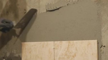 Genç efendi seramik duvar odadaki koyar. O dikkatle geniş banyo içinde yapışkan yüzeyi dikdörtgen levha yerleştirir