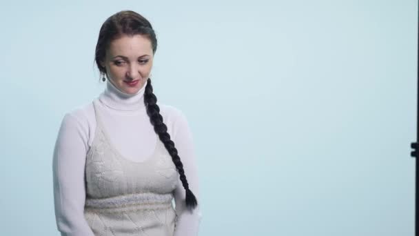Стеснительная молодая женщина на белом фоне — стоковое видео