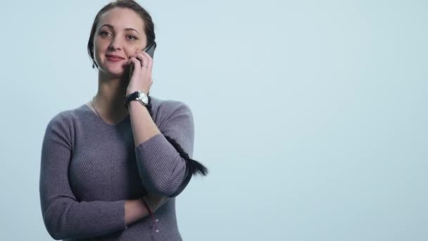 Улыбающаяся счастливая молодая женщина разговаривает на мобильном, изолированном над белым — стоковое видео