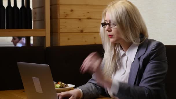 Zakenvrouw eten lunch en werken op de laptop in het café — Stockvideo