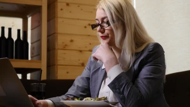 Бізнес-леді їсть обід і працює на ноутбуці в кафе — стокове відео