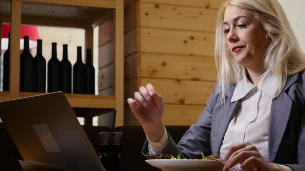 Pengusaha wanita makan siang dan bekerja pada laptop di kafe — Stok Video