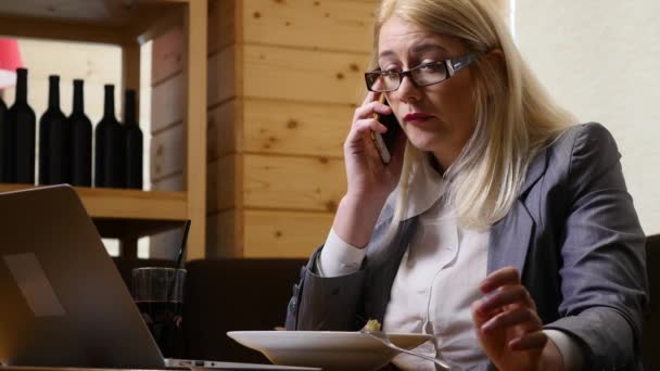 Businesswoman eating lunch and speaking on the phone in the cafe — Stock Video