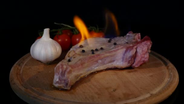 Vista de cerca de la pieza de carne cruda en el fuego girando en la tabla de cortar — Vídeo de stock