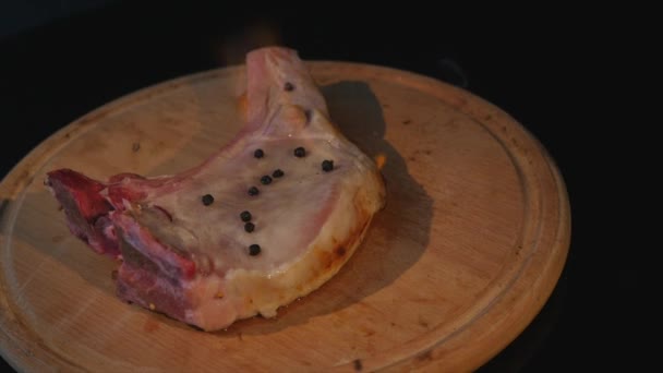 Vista close-up de pedaço cru de carne em fogo girando em tábua de corte — Vídeo de Stock