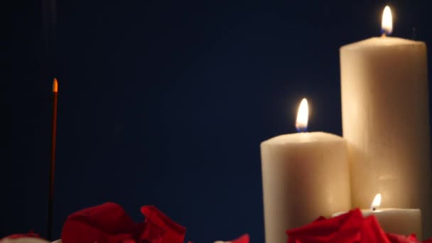 Räucherstäbchen und Kerzen mit Rosenblättern auf dunklem Hintergrund — Stockvideo