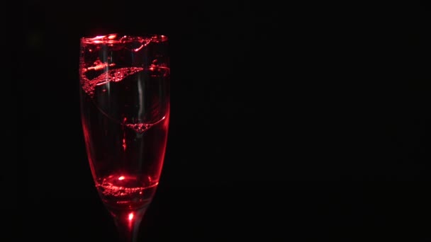 A glass with foam on a black background. Floodlight with a pink filter in the back — Stock Video