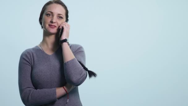 Усміхнена щаслива молода жінка говорить на мобільному телефоні ізольовано над білим — стокове відео