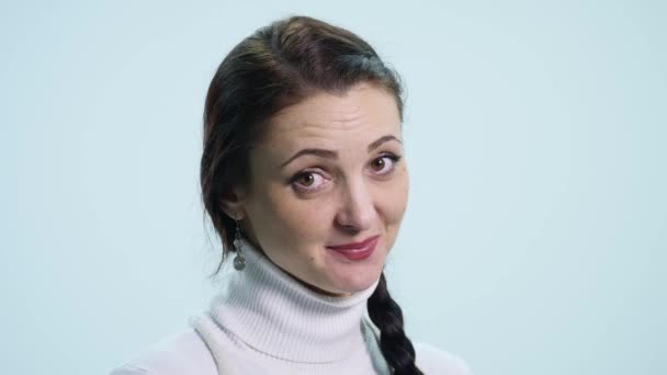 Сором'язлива молода жінка на білому тлі — стокове відео