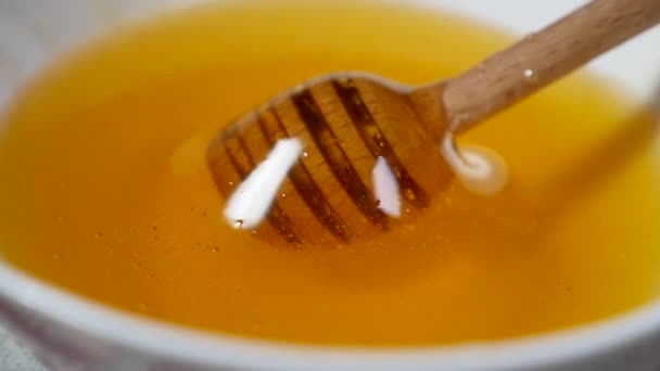 Κοντινό πλάνο του ψιλοβρόχι σχετικά με μια κουτάλα μέλι σε ένα μπολ γεμάτο μέλι μέλι — Αρχείο Βίντεο