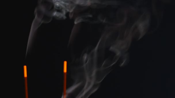 Close up van brandende wierook stokjes met rook op zwarte achtergrond — Stockvideo