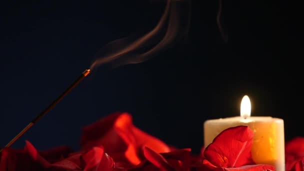 Bastoncini di incenso e candele bruciano e fumano su sfondo scuro, fumo da incenso e luce di candela — Video Stock