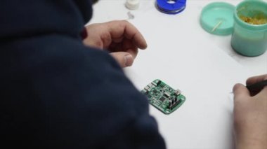 Adam lamba güç kaynağı onarıyor. Halen bir elektronik Pano ve bir havya tutuyor. Üstten Görünüm.