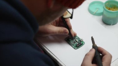 Adam lamba güç kaynağı onarıyor. Halen bir elektronik Pano ve bir havya tutuyor. Üstten Görünüm.