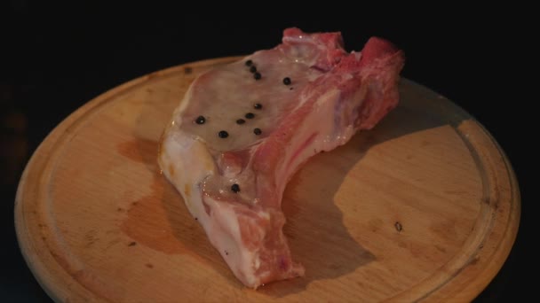 Крупним планом вид сирого шматка м'яса у вогні, що обертається на дошці — стокове відео