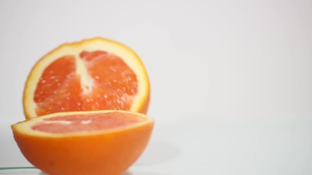 Dos mitades de naranja yacen sobre un fondo blanco. Naranja fresco sobre fondo blanco de cerca — Vídeos de Stock