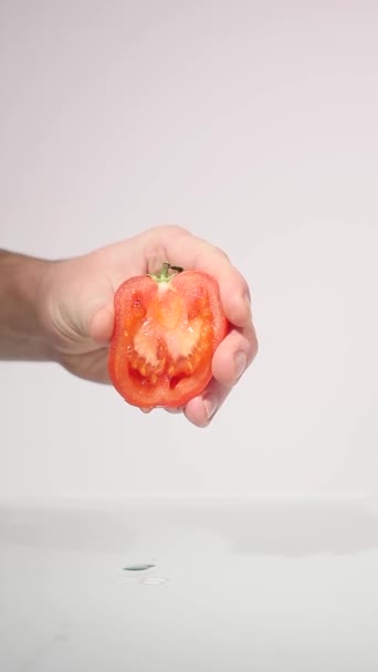 La mano exprime el jugo del tomate — Vídeo de stock
