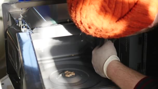 Молодой ремонтник чинит и ремонтирует микроволновую печь — стоковое видео