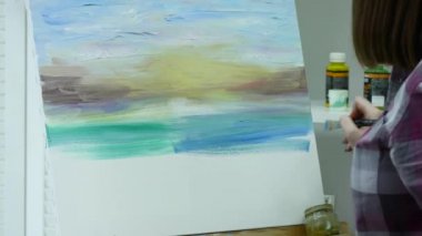 Sanatçının tuval üzerine bir kadın boyar ve geniş bir fırça smear. Tuval şövale üzerinde duruyor. Sanatçı şövale çizer