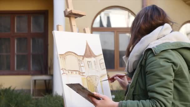 Jóvenes artistas dibujan en la ciudad. Artistas pintando cuadros en la calle. Los estudiantes pintan la construcción de la vieja ciudad europea — Vídeo de stock