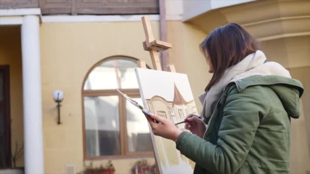 Jóvenes artistas dibujan en la ciudad. Artistas pintando cuadros en la calle. Los estudiantes pintan la construcción de la vieja ciudad europea — Vídeos de Stock