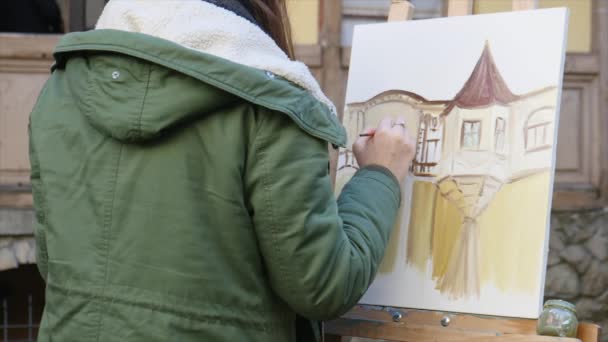 Jóvenes artistas dibujan en la ciudad. Artistas pintando cuadros en la calle. Los estudiantes pintan la construcción de la vieja ciudad europea — Vídeos de Stock