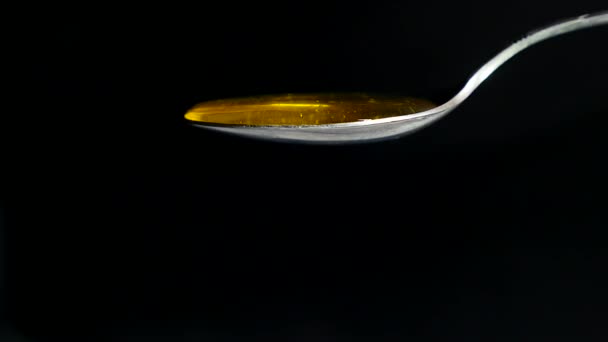 Honey Flowing from Spoon against Black Background — Stock Video