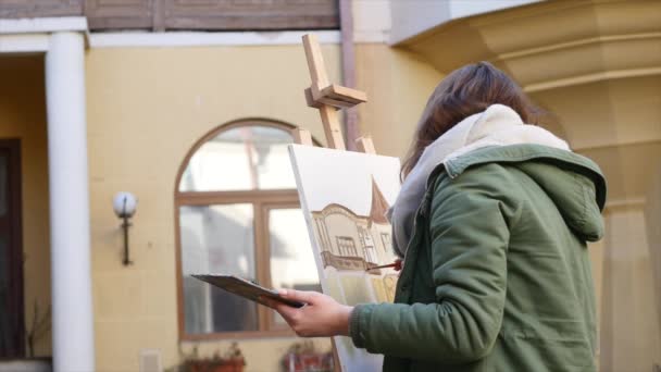 Jóvenes artistas dibujan en la ciudad. Artistas pintando cuadros en la calle. Los estudiantes pintan la construcción de la vieja ciudad europea — Vídeos de Stock