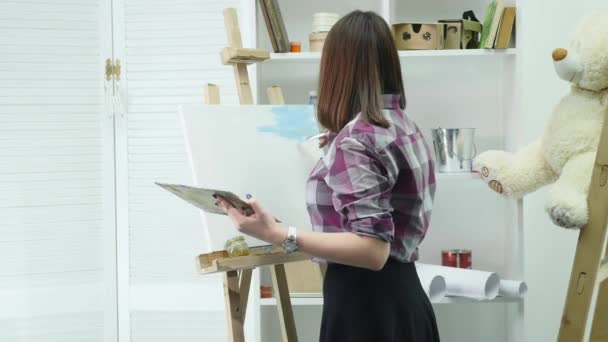 El artista llega a la imagen y comienza a pintar al óleo en un estudio brillante. Artista masculino creativo dibujo cuadro con pinturas al óleo en el estudio — Vídeo de stock