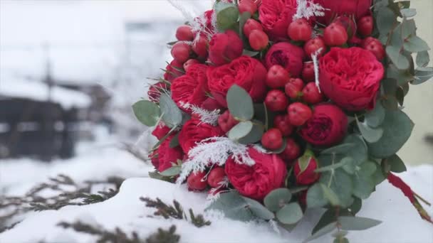 Ramo de boda con anillos de boda con flores rojas en el fondo de la nieve — Vídeo de stock