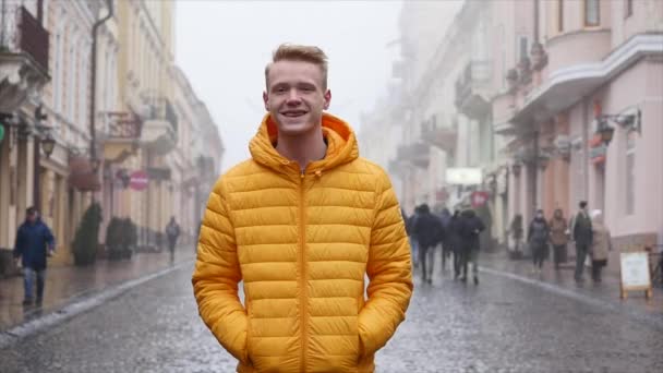 Retrato de atractivo joven serio y elegante mirando a la cámara y sonriendo en la ciudad — Vídeo de stock