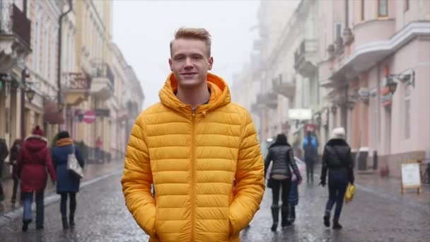 Joven sonriendo y mirando a la cámara. Retrato de un joven guapo feliz en una calle urbana — Vídeos de Stock