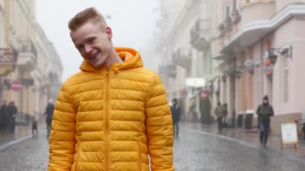 Junger gutaussehender Mann ist zu schüchtern, um vor der Kamera zu posieren, aber trotzdem versucht er, Fotomodell zu sein und zu lächeln — Stockvideo