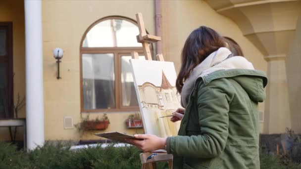 Jovens artistas atraem a cidade. Artistas a pintar quadros na rua. Estudantes pintam a construção da velha cidade europeia — Vídeo de Stock