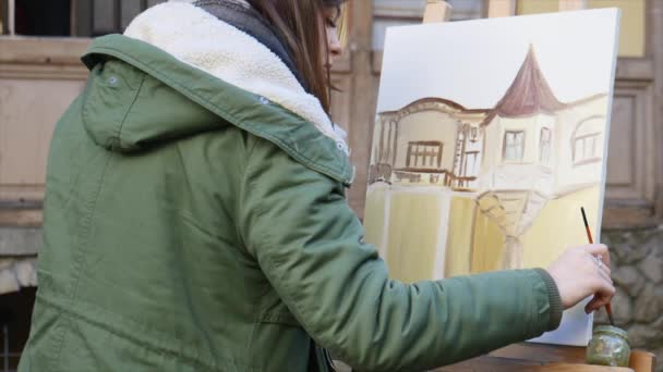 Jóvenes artistas dibujan en la ciudad. Artistas pintando cuadros en la calle. Los estudiantes pintan la construcción de la vieja ciudad europea — Vídeos de Stock